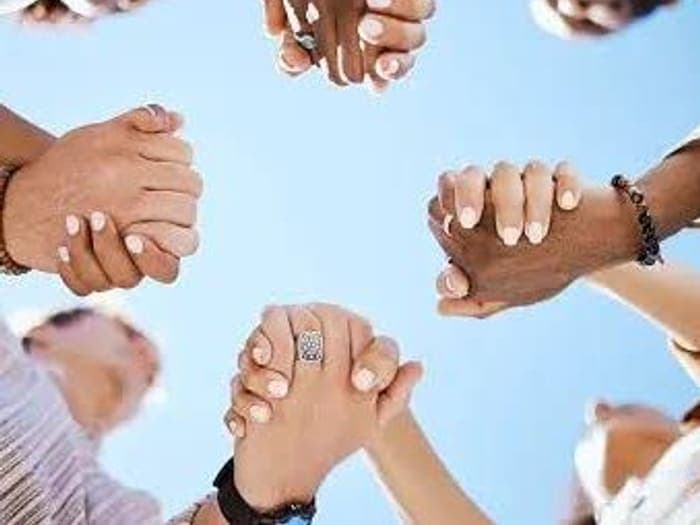 Hands joined together in a circle against the sky