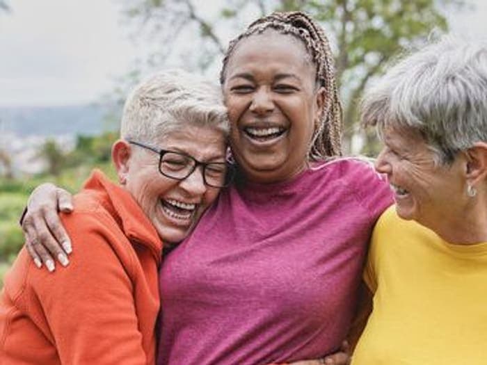 Three senior women laughing together outdoors